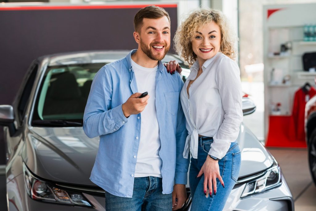 Happy couple in car dealership on the background of their new car